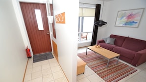 Een moderne woonkamer met een rode bank, een houten salontafel en een kamerkleed met een patroon.