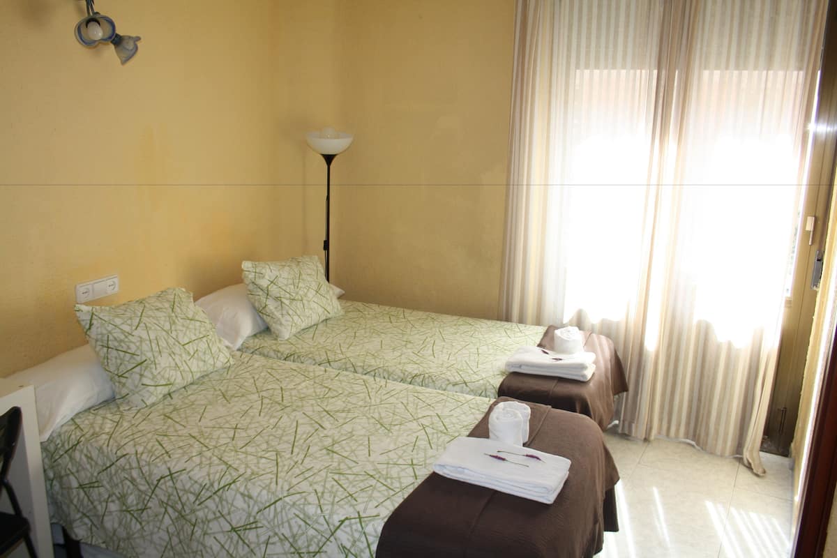 Une chambre d’hôtel avec deux lits, une lampe et une fenêtre avec des rideaux.