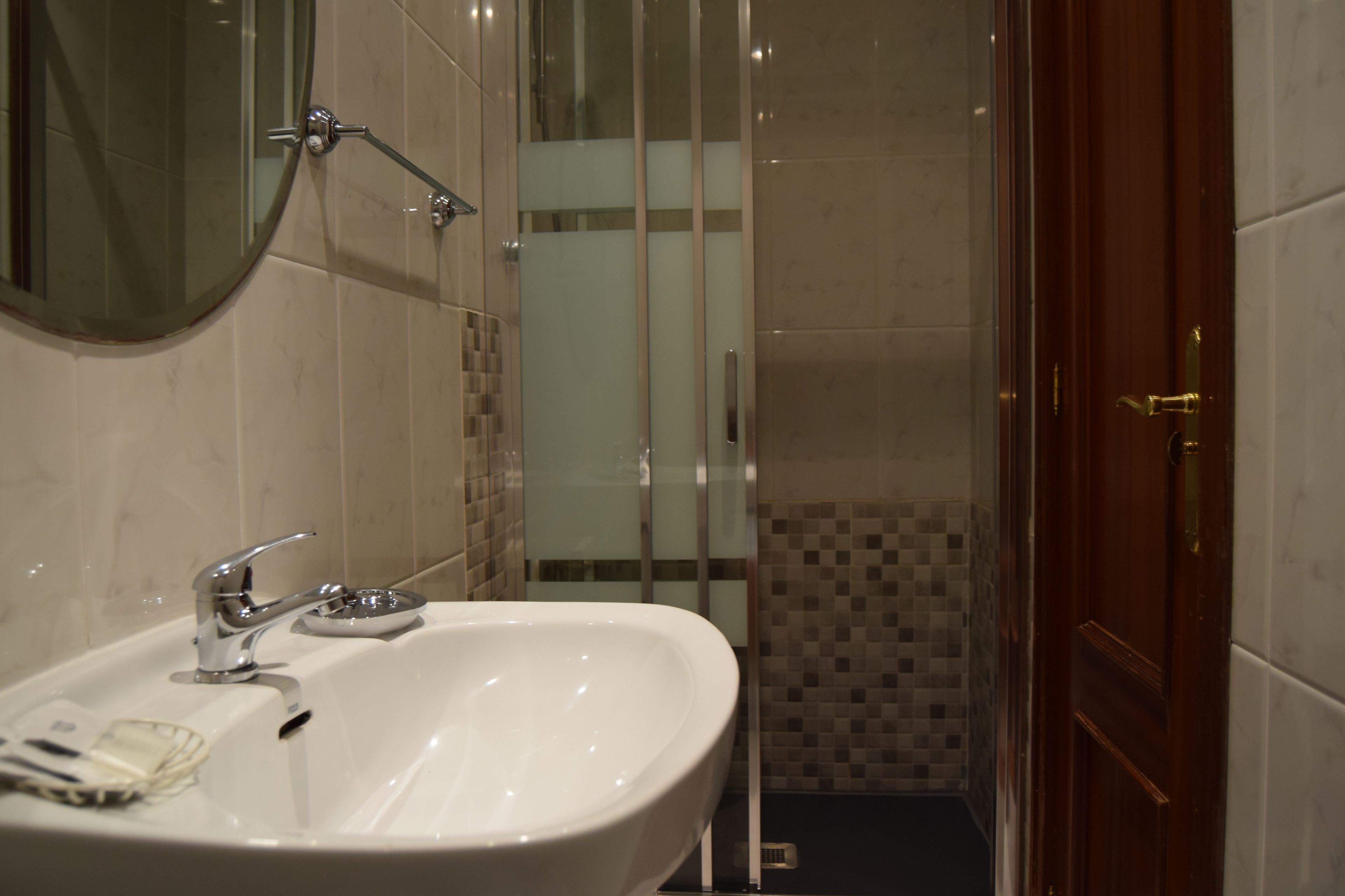 A bathroom with a white sink, a mirror, and a shower area.