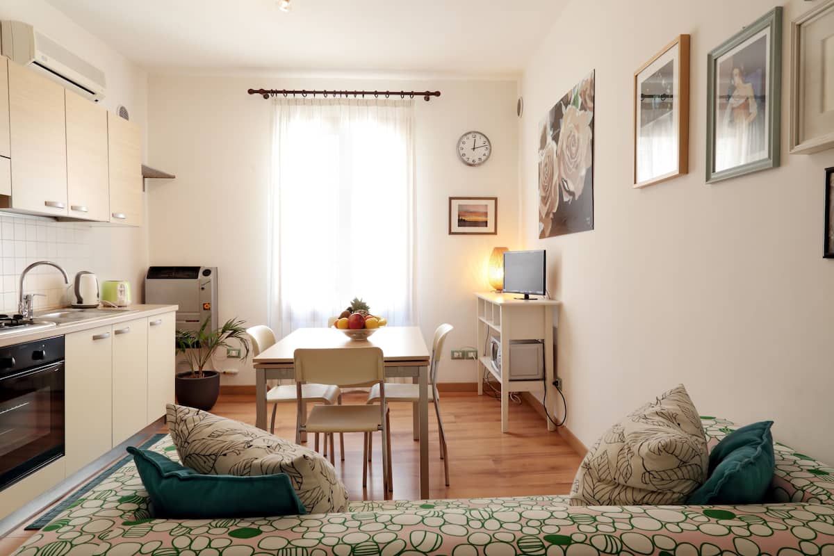 A compact living space with a kitchenette, dining area, and a bed with patterned bedding.