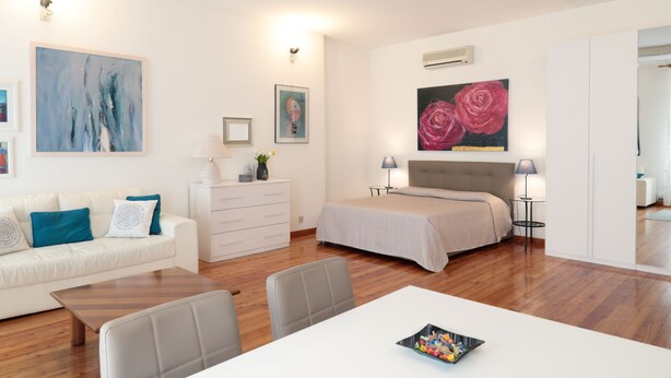 A modern hotel room with a bed, a sofa, a dining table, and a small kitchen area. - Padovaresidence Piazza delle Erbe (Padova)