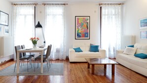 A living room with a white sofa, a coffee table, a dining table with chairs, and a lamp. - Padovaresidence Piazza delle Erbe (Padova)