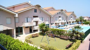 A residential building with a swimming pool, a children's play area, and a well-maintained garden.