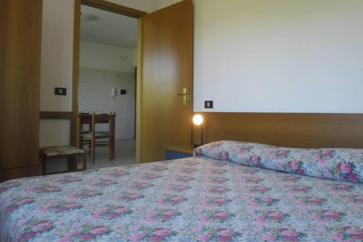 A bedroom with a bed, a chair, and a door leading to another room.