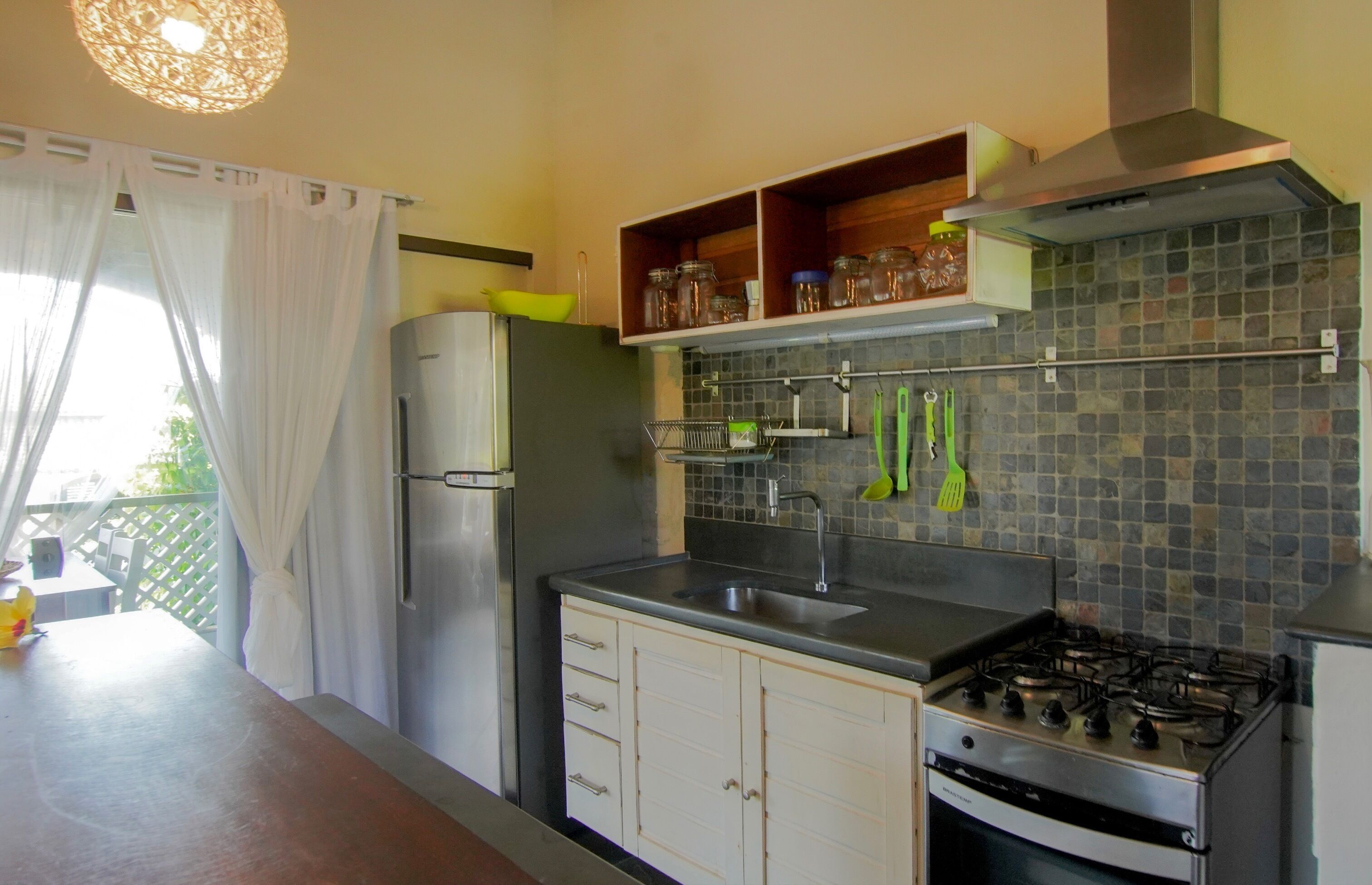 A compact kitchen with a refrigerator, stove, and a tiled backsplash.