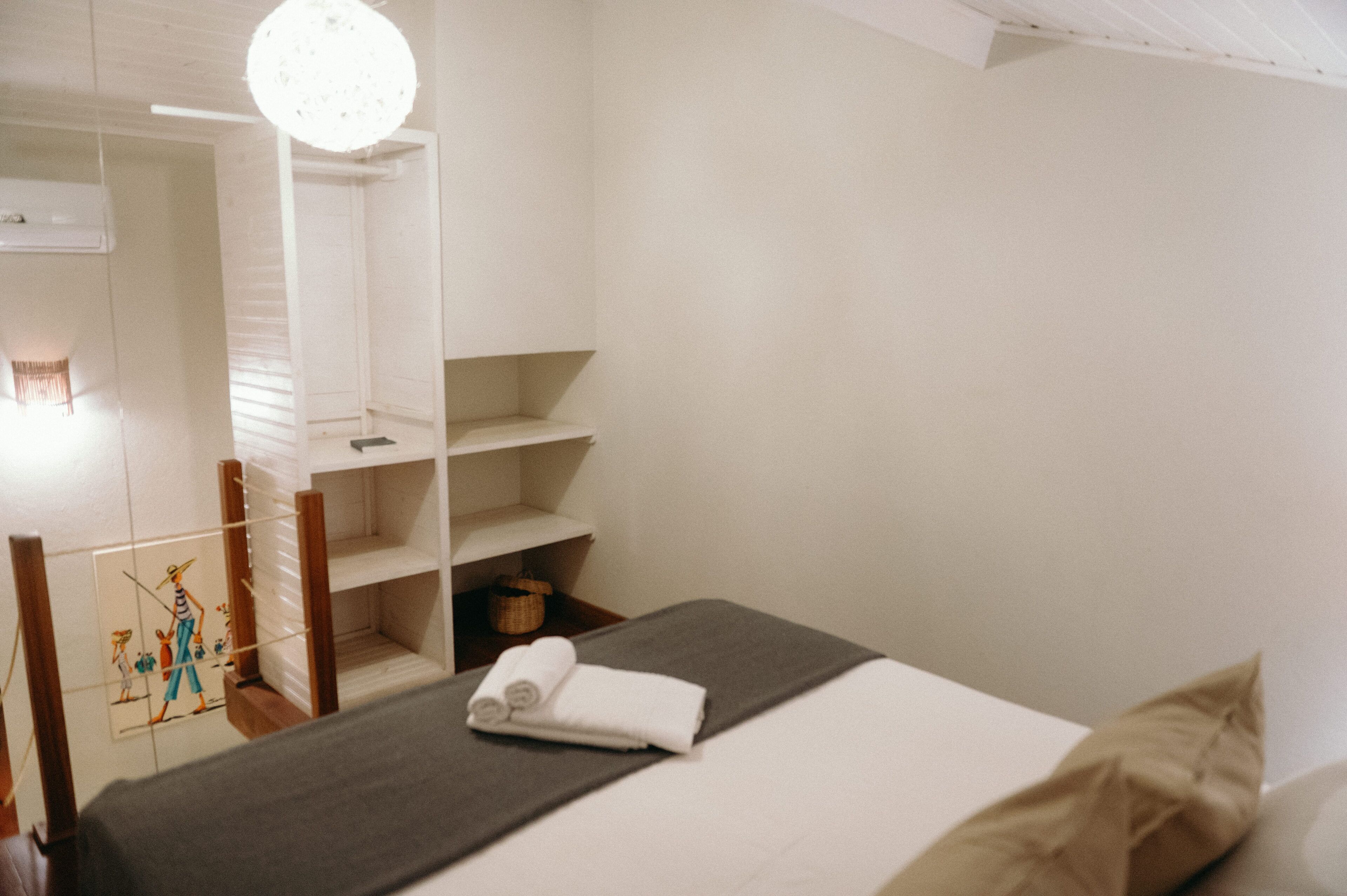 Quarto de hotel com uma cama, mesa de cabeceira, espelho e guarda-roupa.