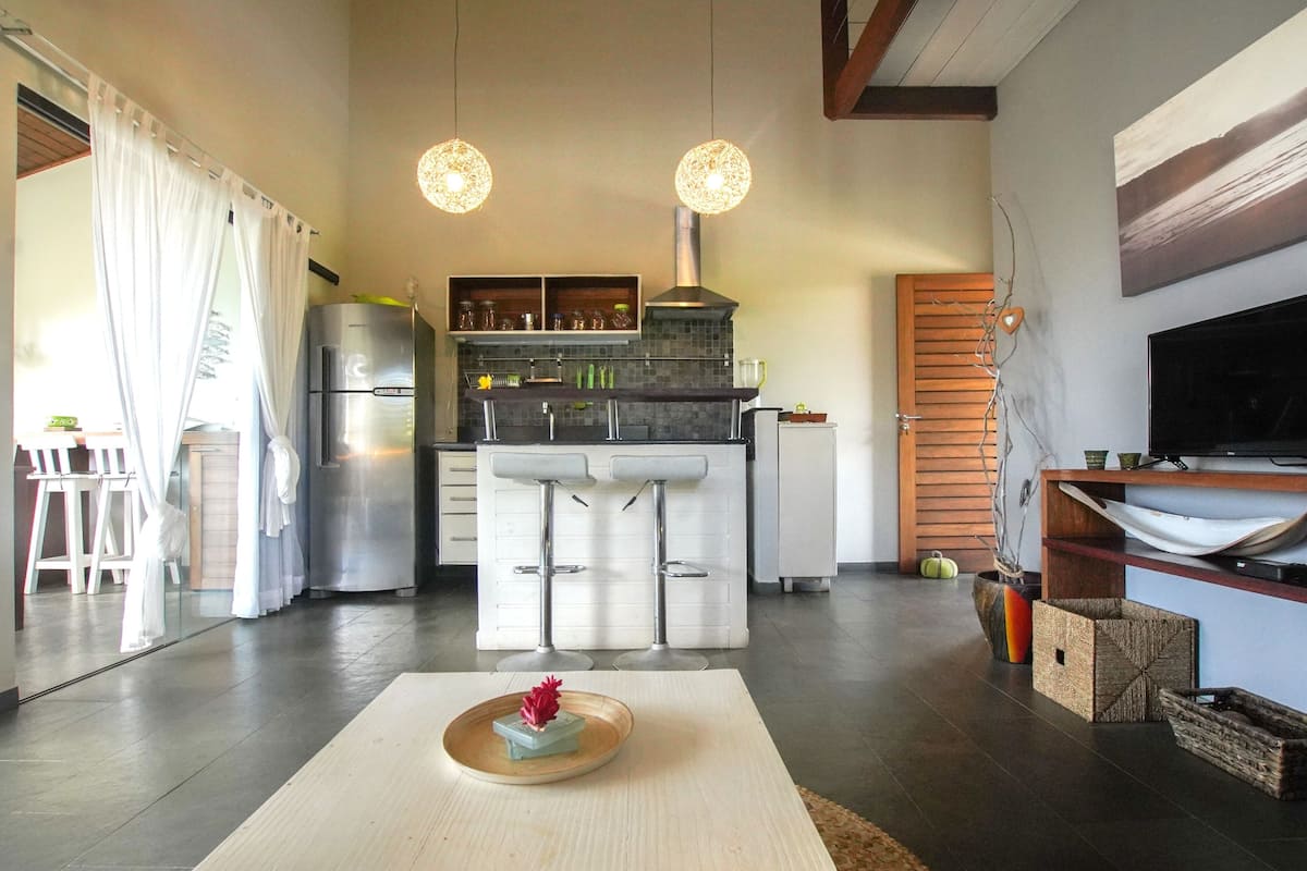 A modern kitchen with a central island, bar stools, and pendant lighting.