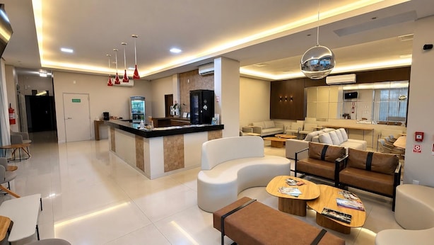 A modern hotel lobby with a reception desk, seating area, and a kitchenette. - Mac Hotel (Palmas)