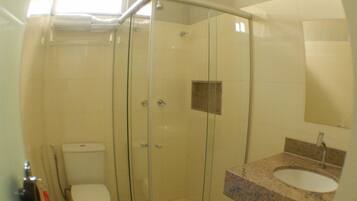 A bathroom with a glass-enclosed shower, a toilet, and a sink with a granite countertop.