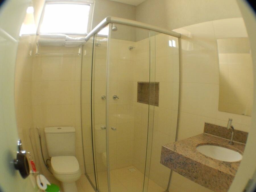 A bathroom with a glass-enclosed shower, a toilet, and a sink with a granite countertop.