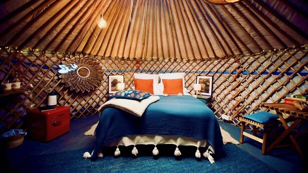 A yurt with a bed, a red cabinet, and a hanging light fixture. - Wester Auchraw Croft B&B (Lochearnhead)