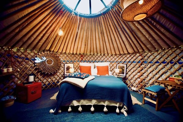 A yurt with a bed, a red cabinet, and a hanging light fixture. - Wester Auchraw Croft B&B (Lochearnhead)
