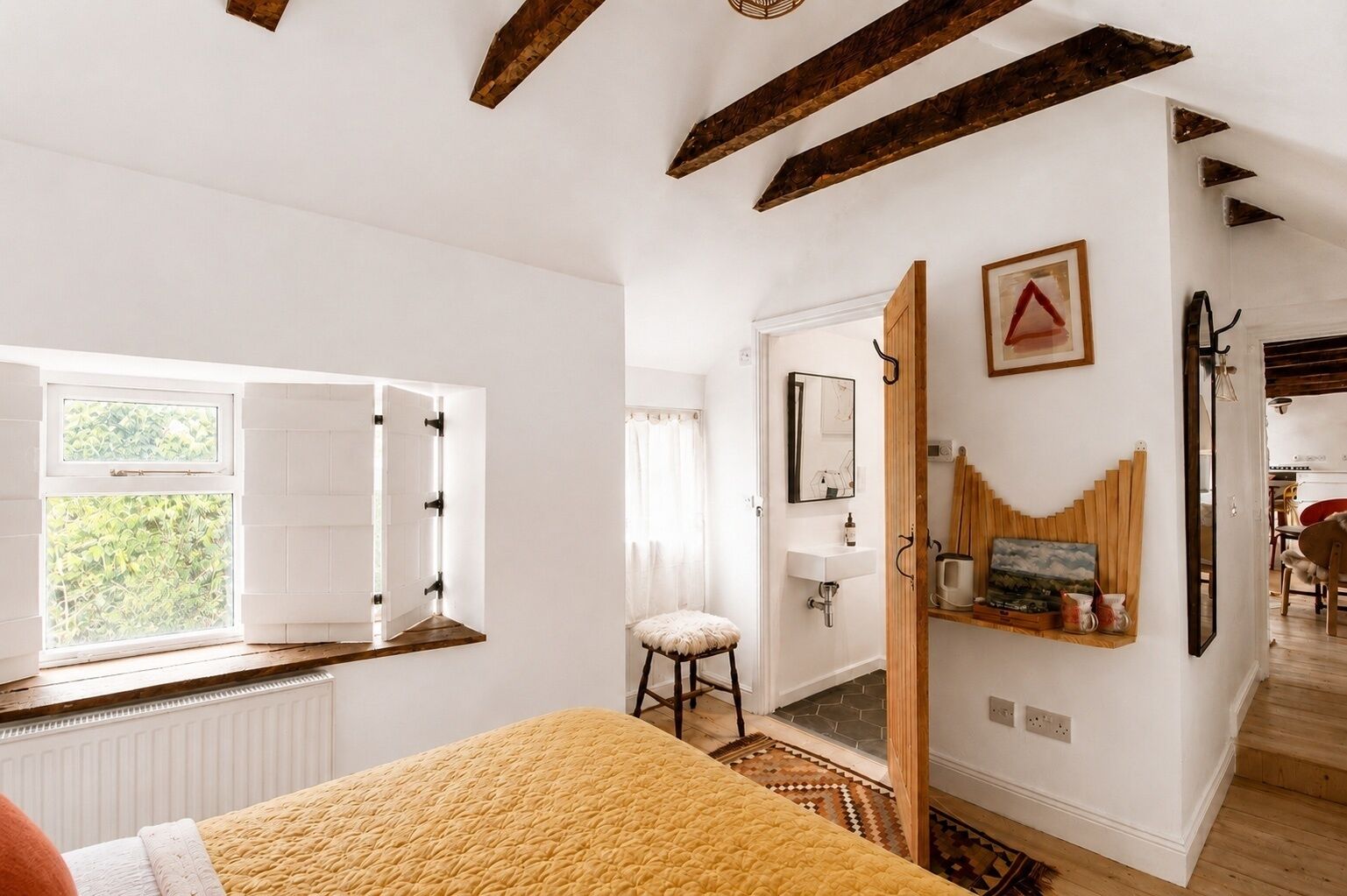 Quarto com cama, janela, porta, pia e espelho.