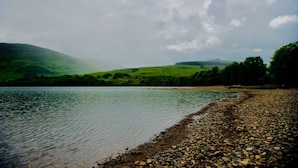 A lake with a pebble beach and green hills in the background. - Wester Auchraw Croft B&B (Lochearnhead)