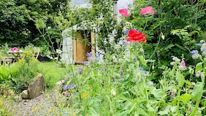 A garden with a wooden structure, surrounded by various flowers and plants. - Wester Auchraw Croft B&B (Lochearnhead)