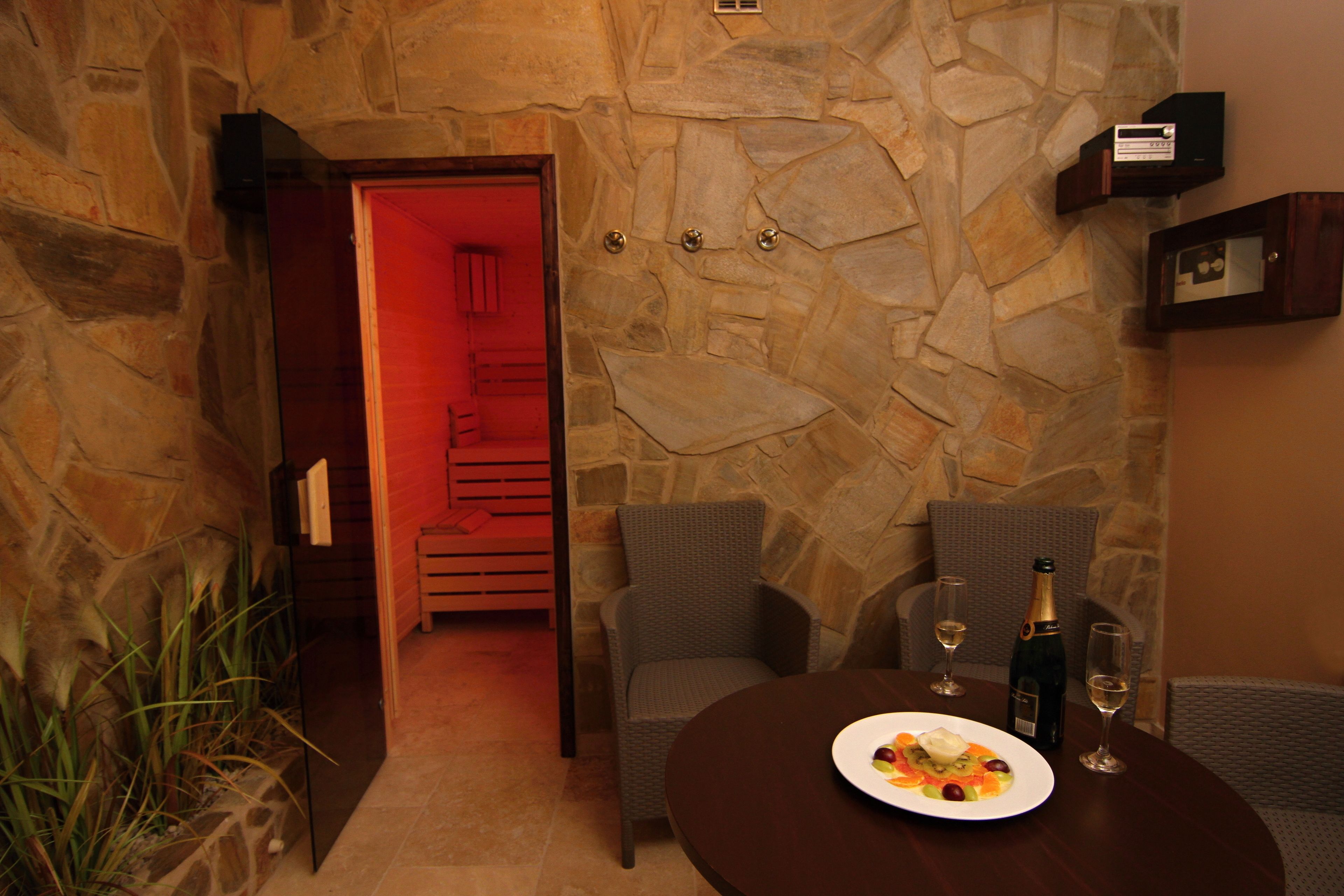 A stone-walled room with a dining table set for two, a bottle of champagne, and two glasses.