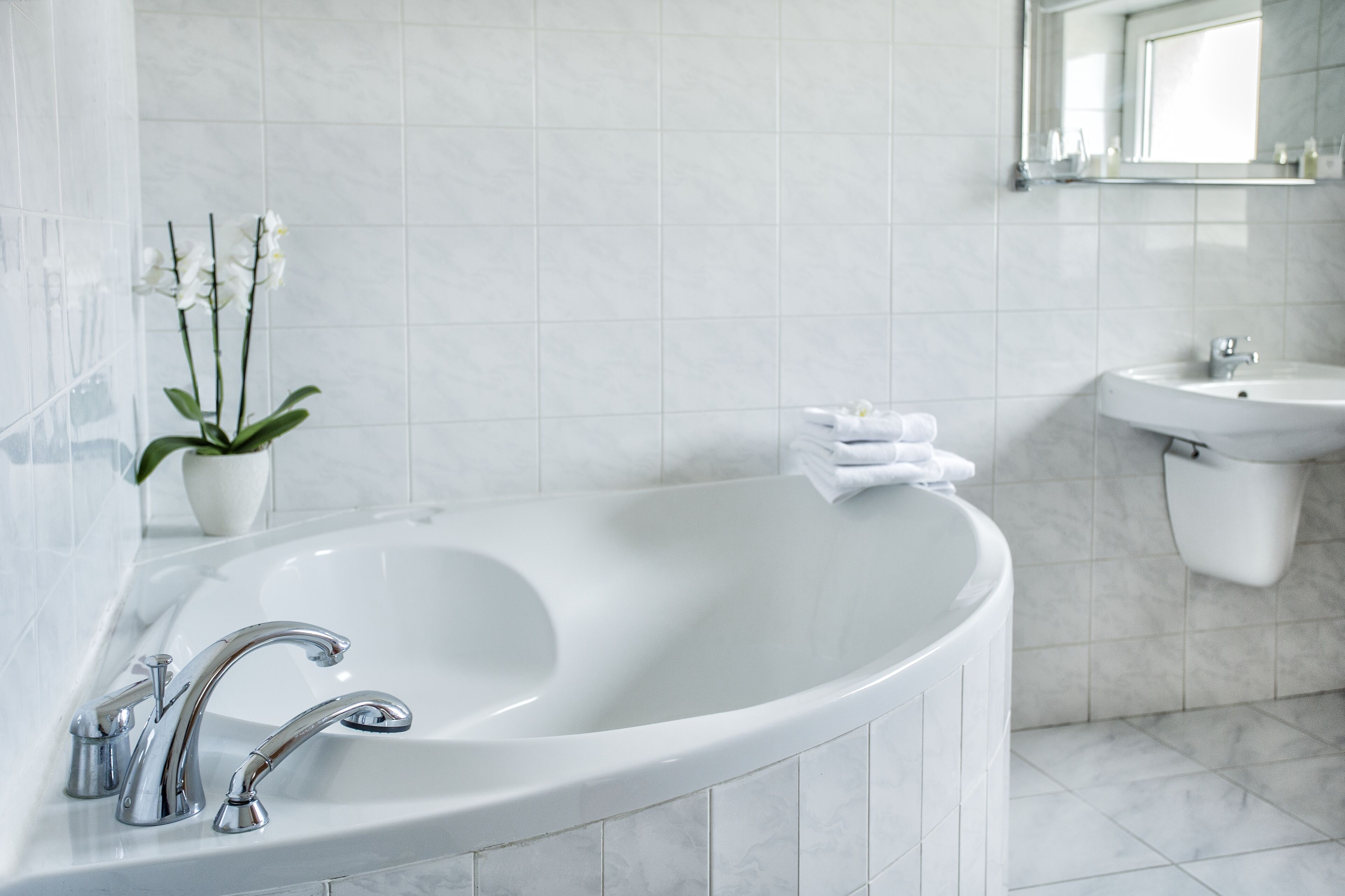 A modern bathroom with a freestanding bathtub, a sink, and a mirror above the sink.
