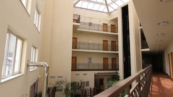 A multi-level atrium with balconies, a central staircase, and potted plants.