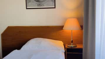A neatly made bed with white linens and blue bedding, a bedside lamp, and a framed artwork on the wall.