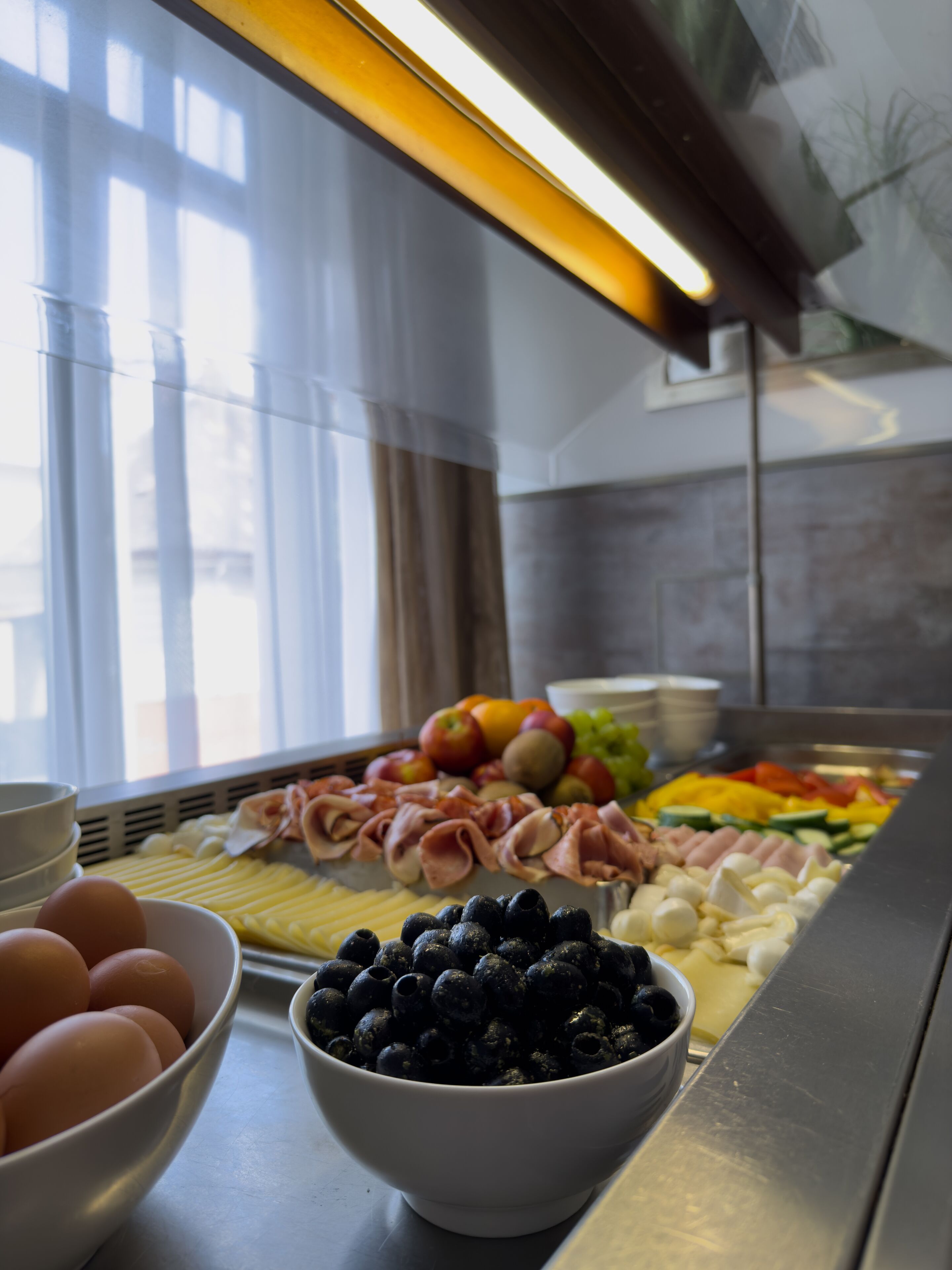 A buffet with various food items including eggs, blueberries, ham, and vegetables.