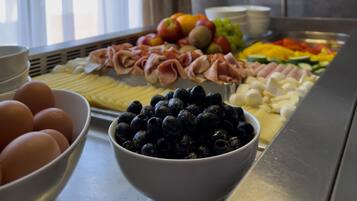 A buffet with various food items including eggs, blueberries, ham, and vegetables.