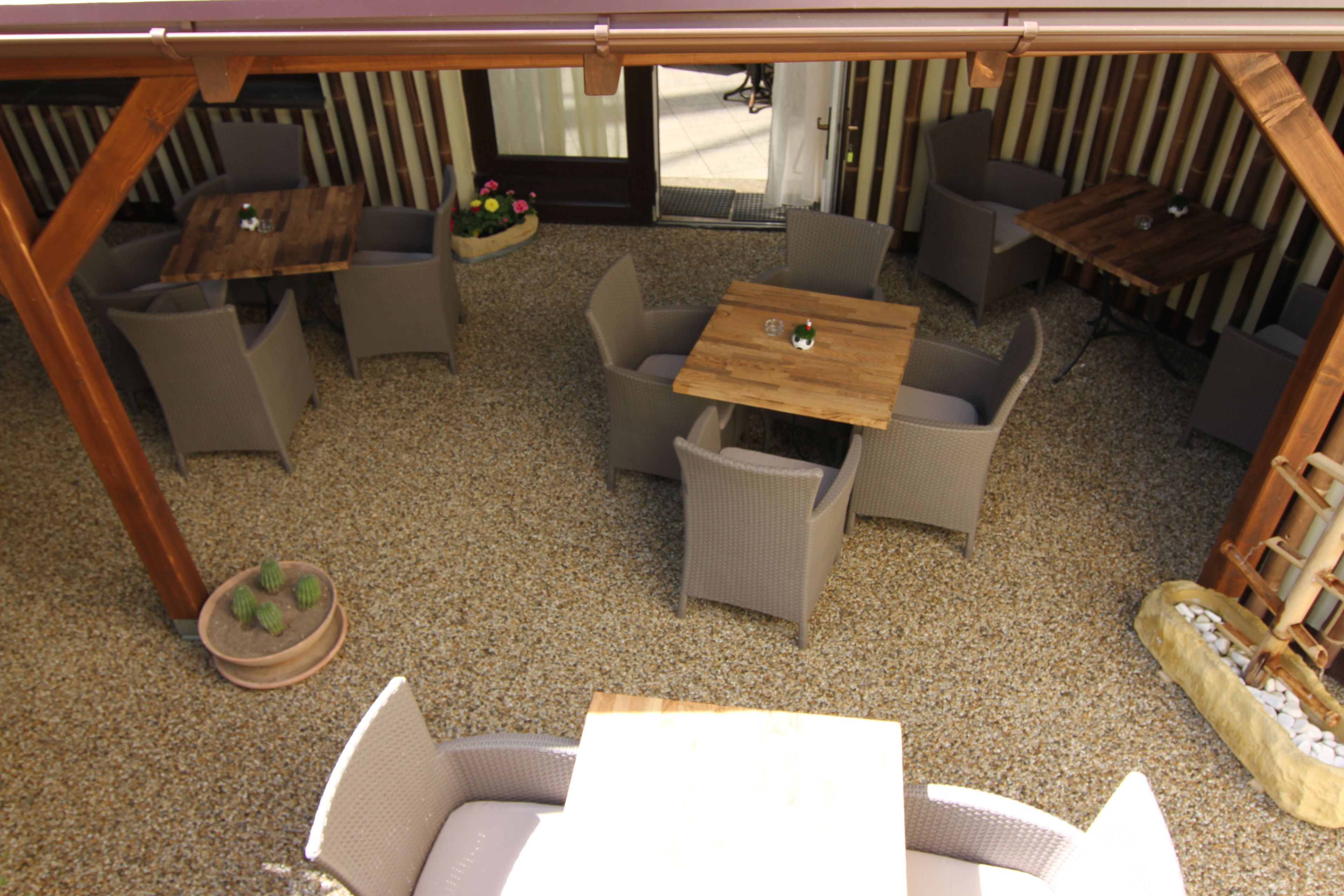 An outdoor patio area with wicker furniture, a wooden table, and a small potted plant.