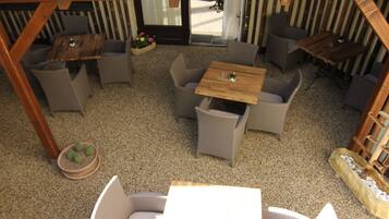 An outdoor patio area with wicker furniture, a wooden table, and a small potted plant.