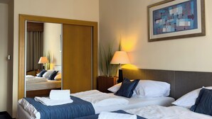 A hotel room with two beds, a large mirror, a painting on the wall, and a lamp. - Hotel Theresia Kolín (Kolin)