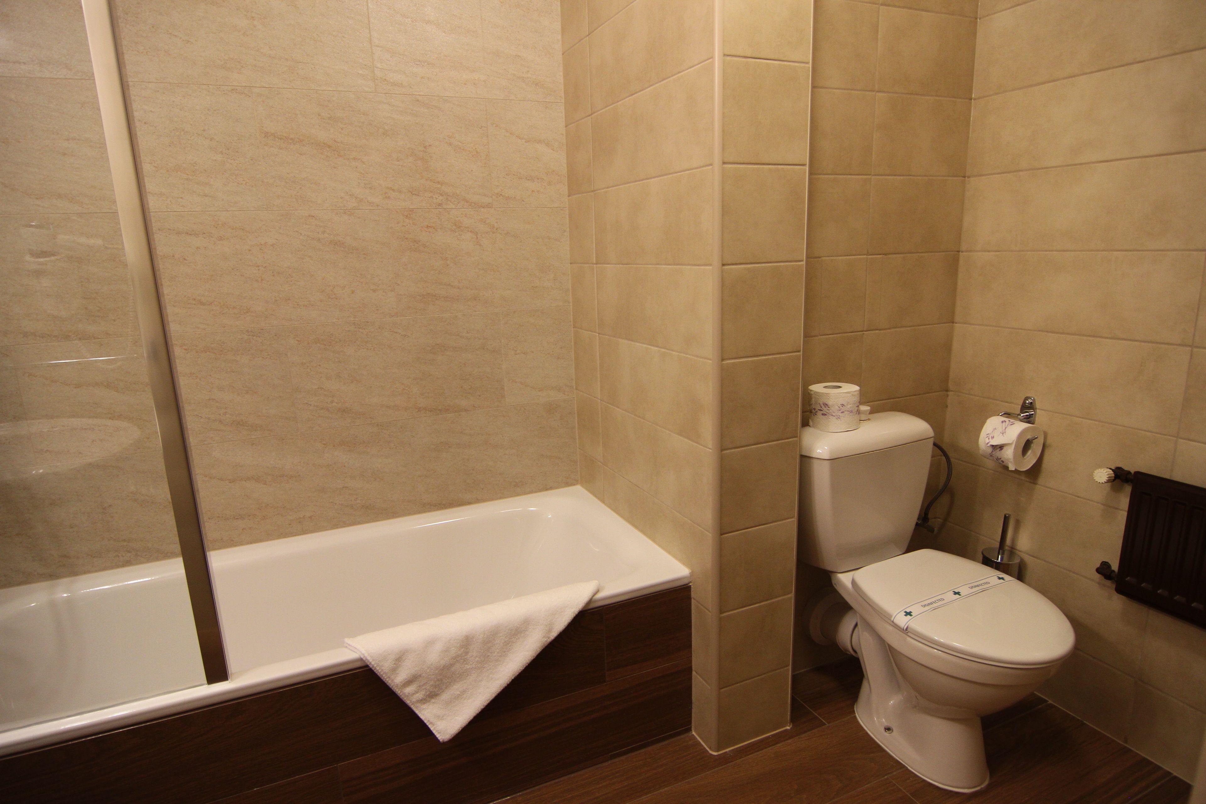 A bathroom with a bathtub, toilet, and a shower area.