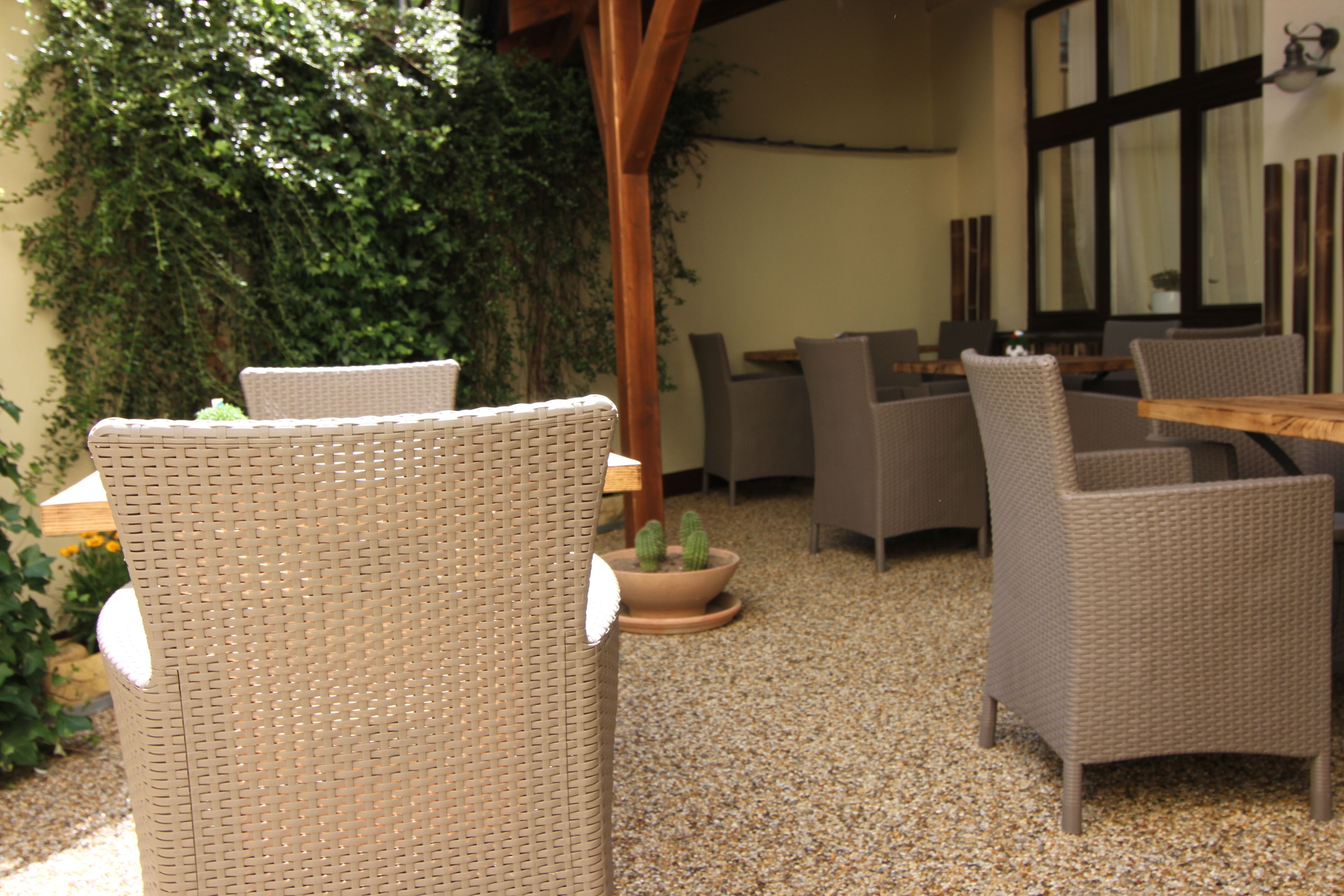 A patio area with wicker furniture, a wooden table, and a potted cactus.