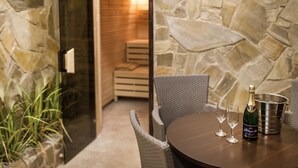 A stone wall, a wicker chair, a table with a bottle of champagne and two glasses, and a metal bucket. - Hotel Theresia Kolín (Kolin)