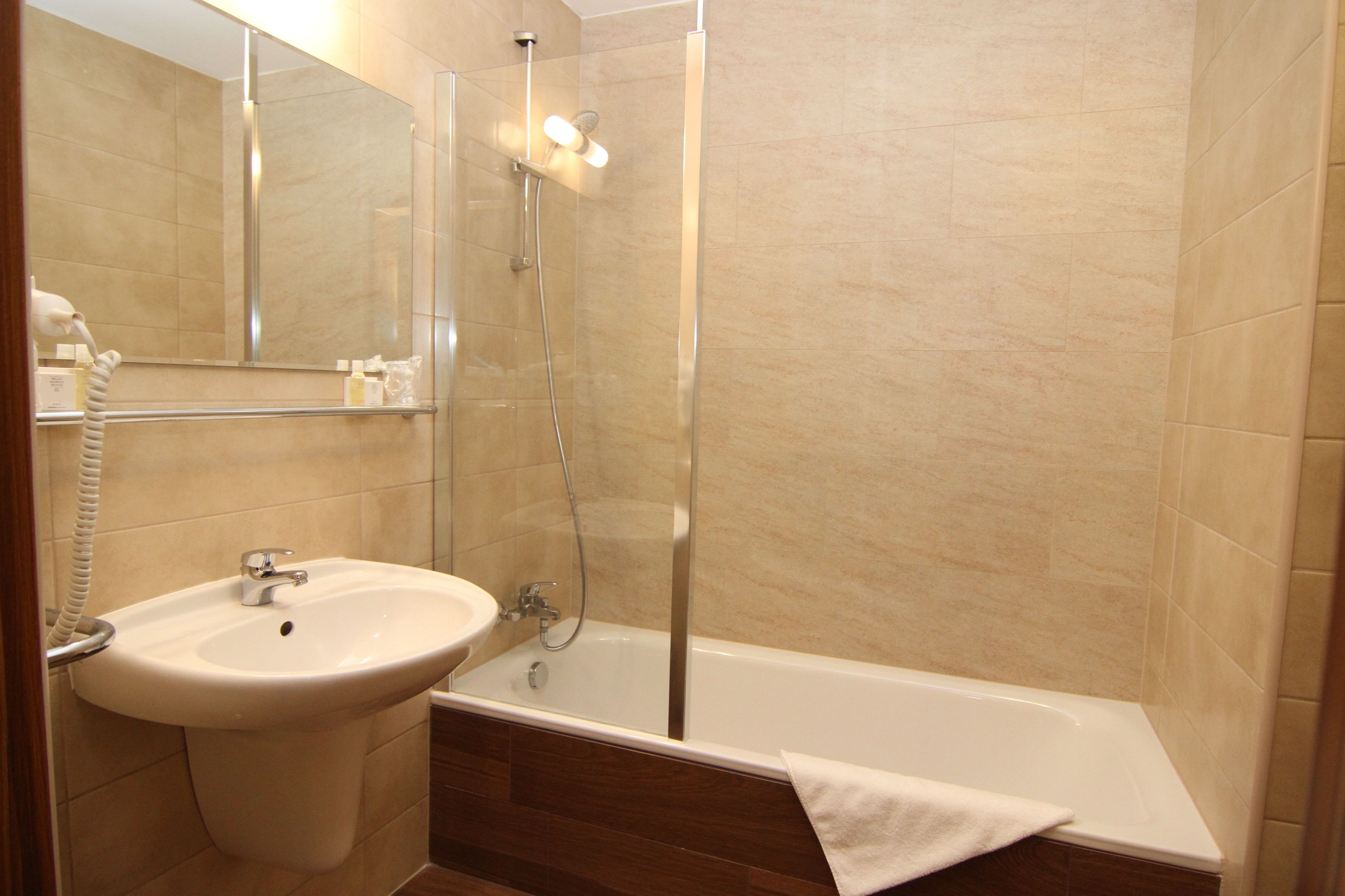 A bathroom with a sink, mirror, and shower.