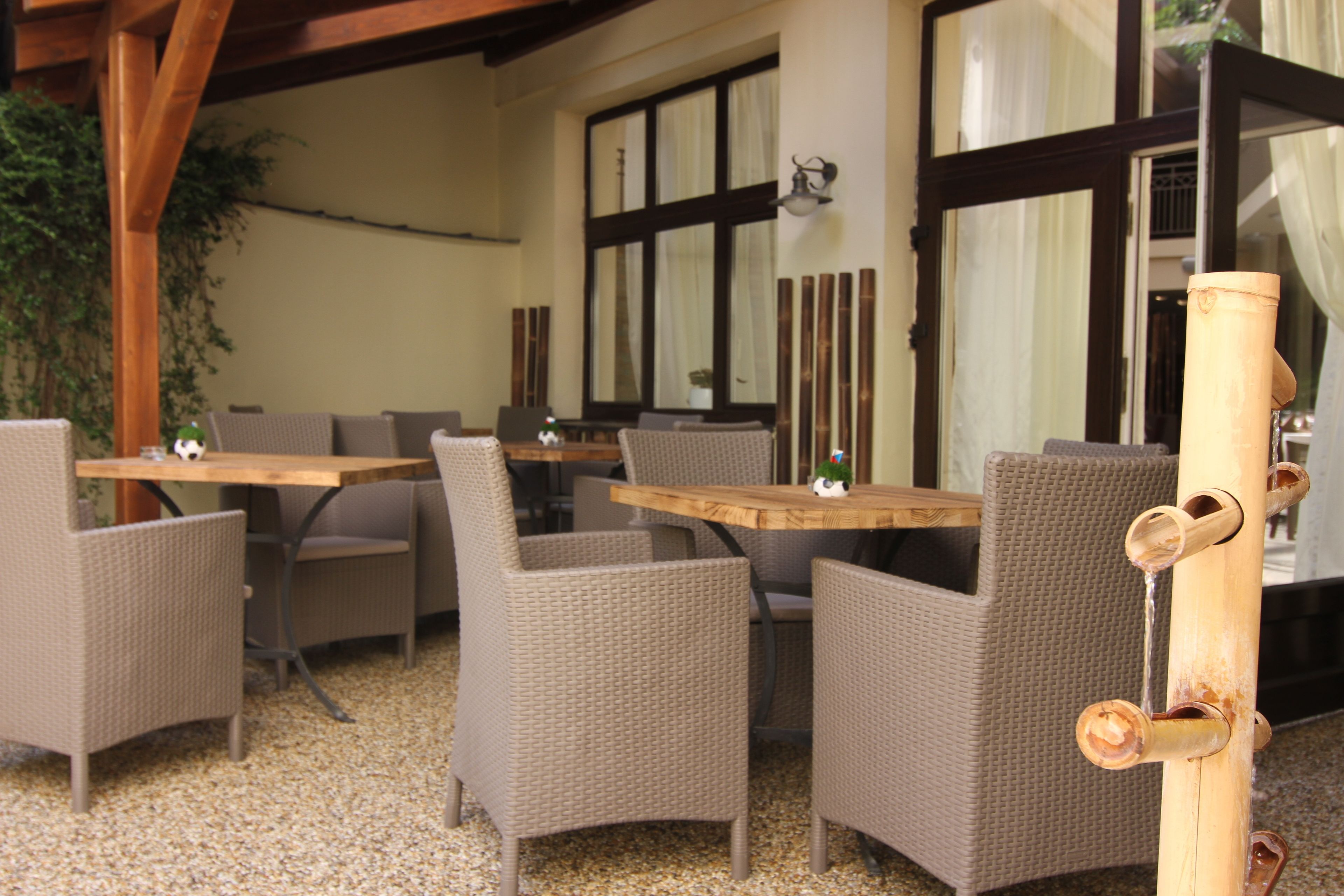 Uma área de estar externa com mobiliário de vime e uma mesa de madeira.