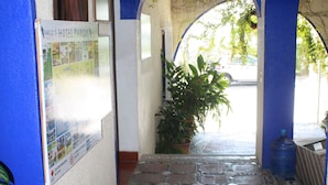 A hallway with tiled flooring, blue arches, and a poster on the wall. - Pargo's Hotel (Puerto Escondido)