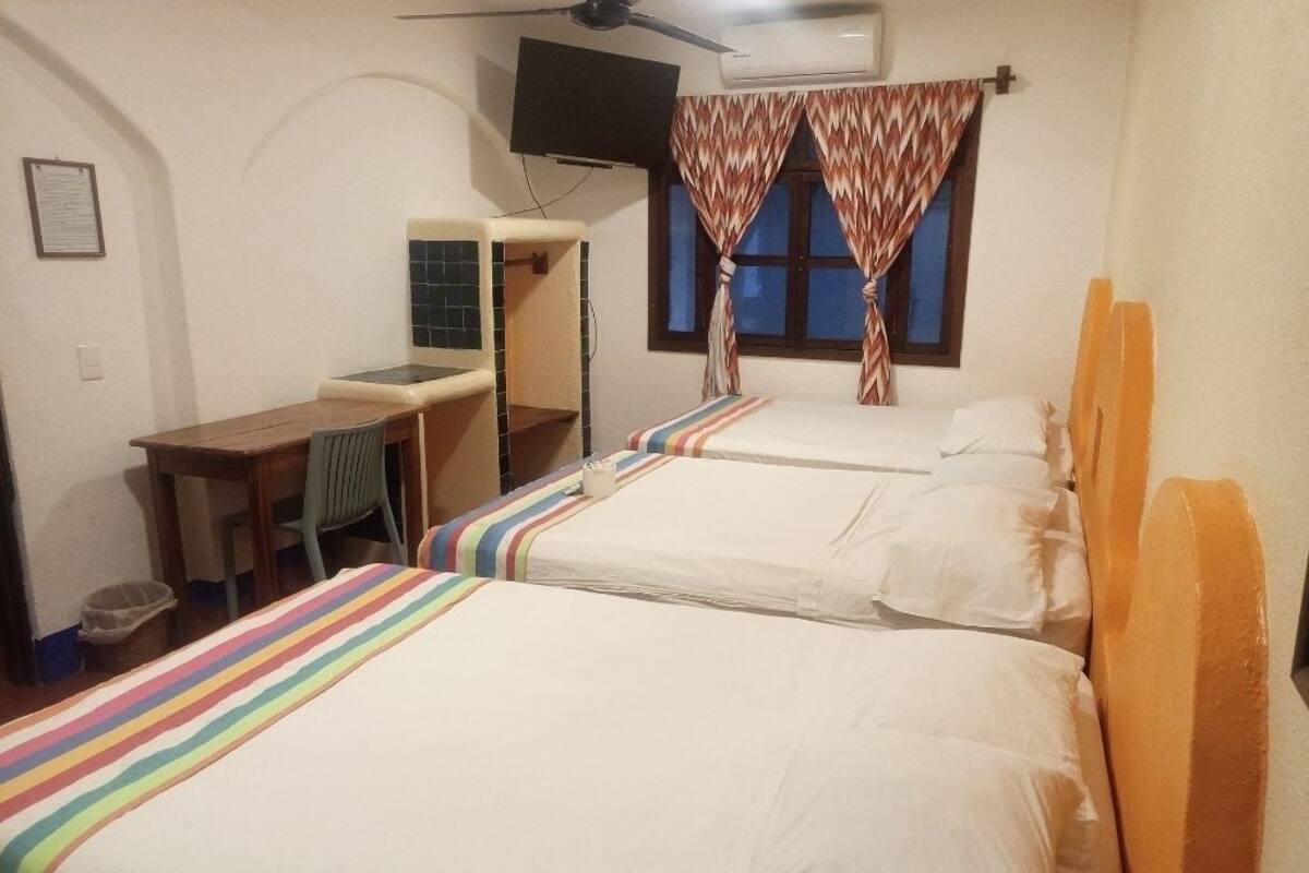 Una habitación de hotel con tres camas, un escritorio y un televisor.