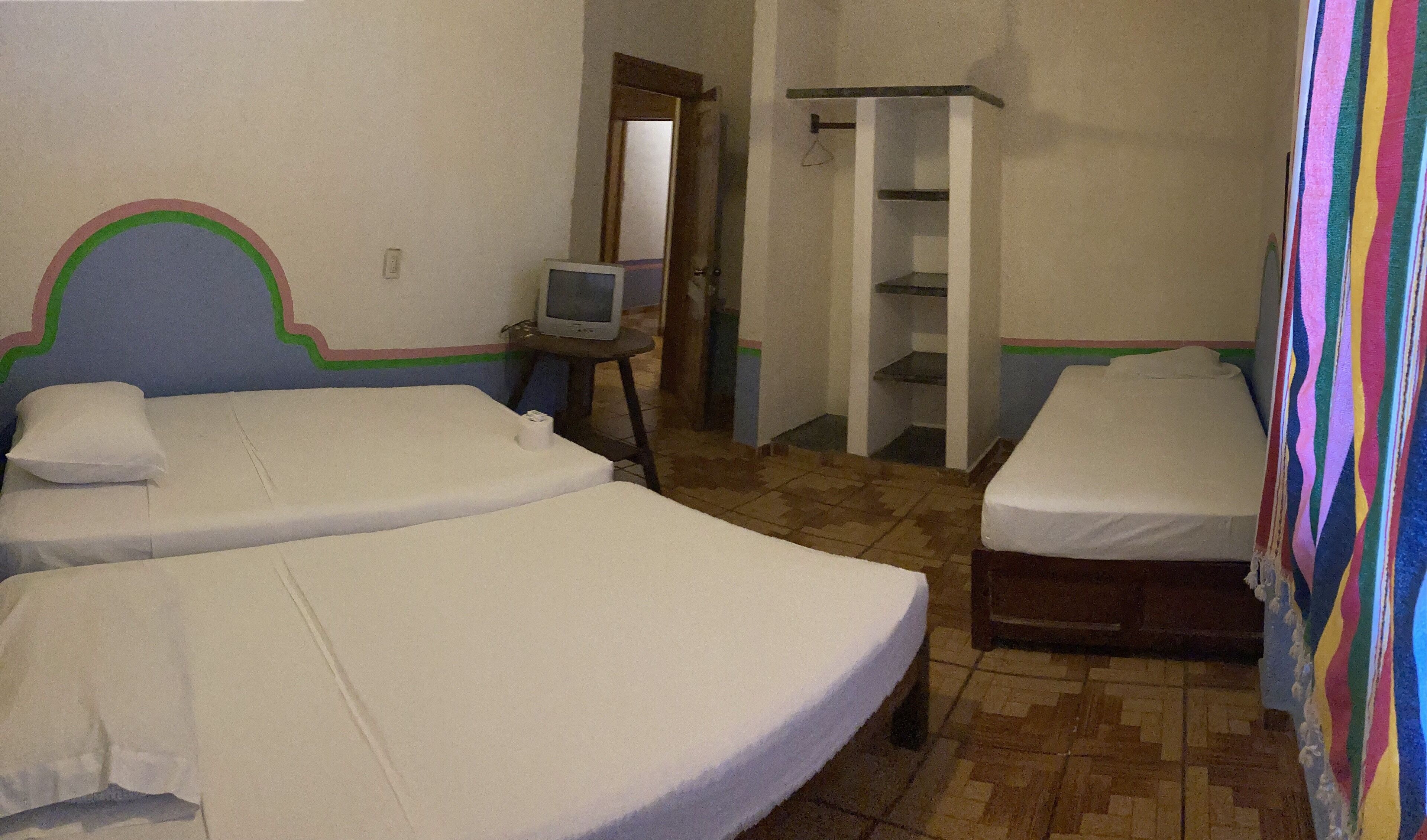 A room with two beds, a television on a small table, and a wardrobe.