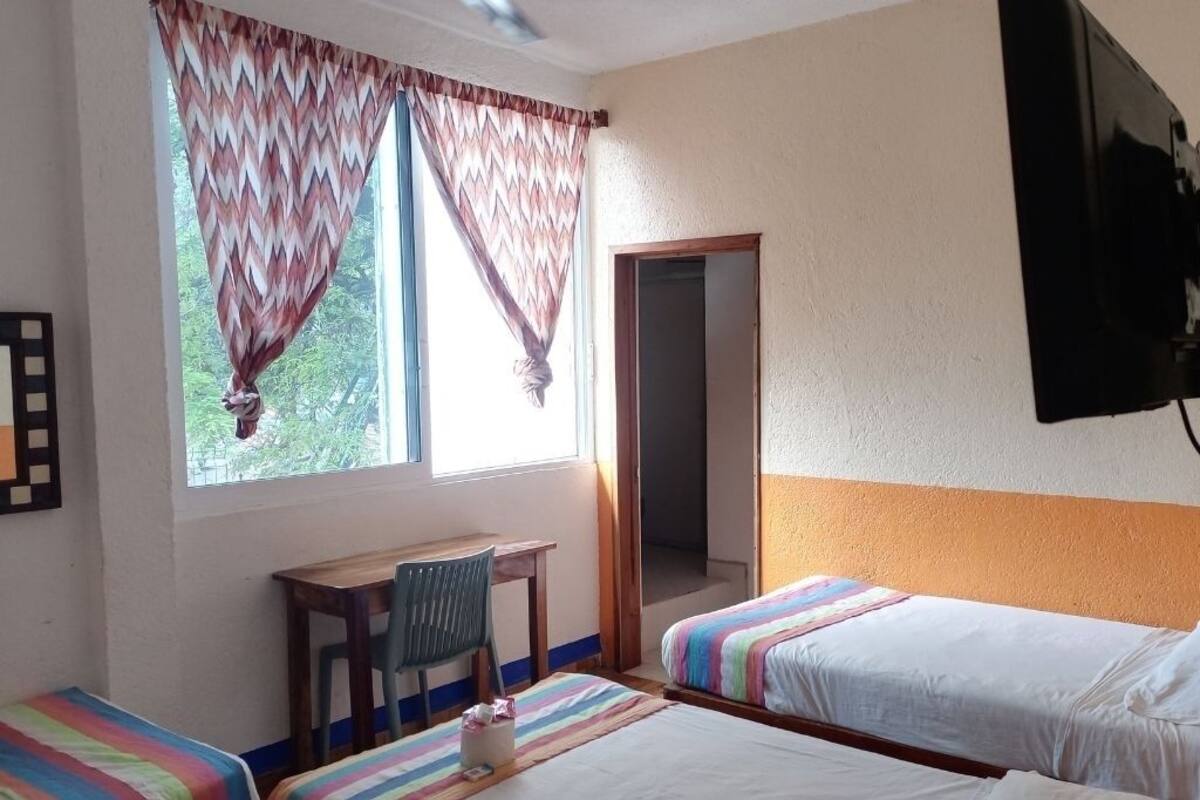 Un dormitorio con dos camas individuales, un escritorio, una silla y un televisor.