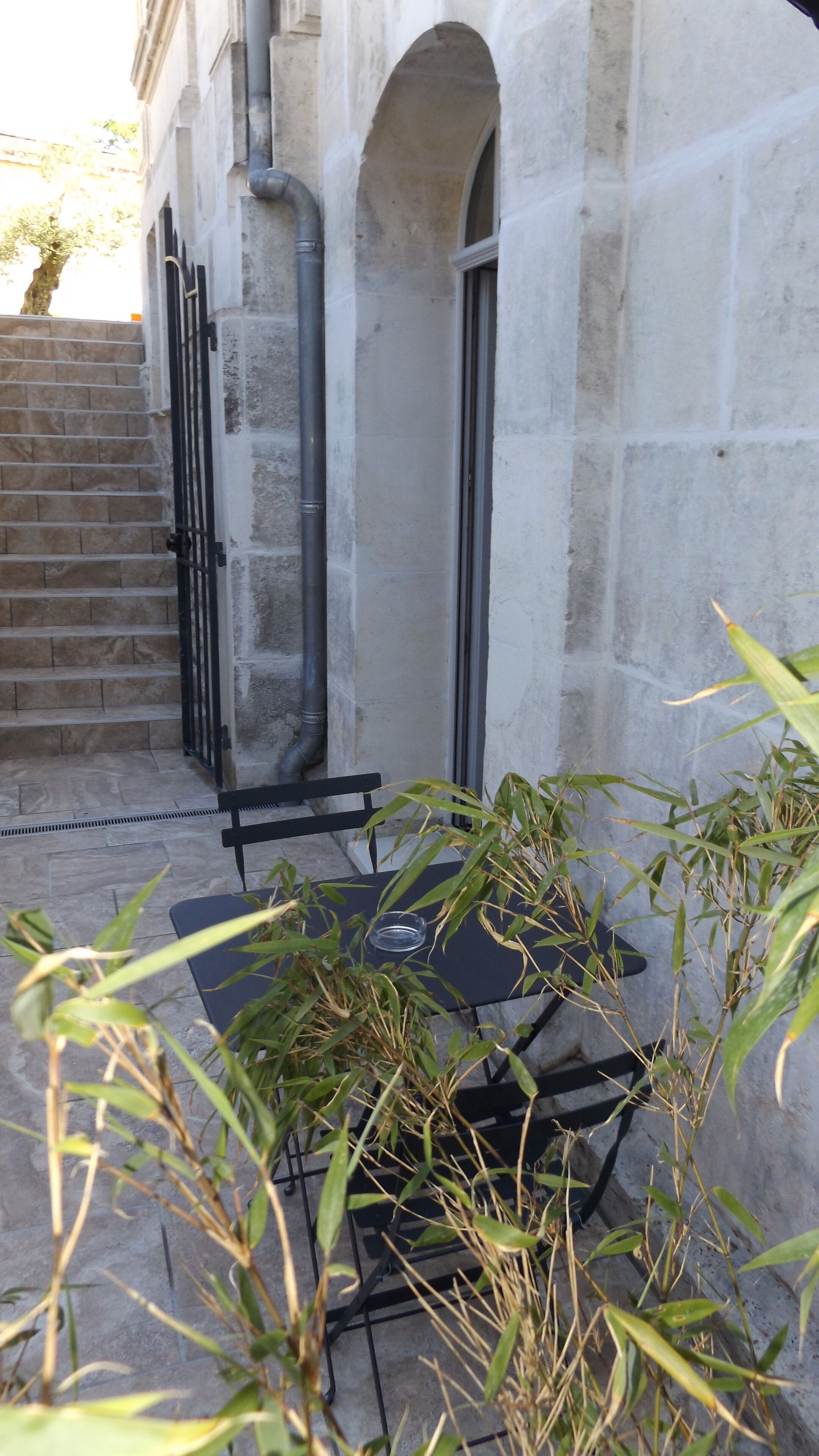 A stone building with a black metal gate, a small table, and a chair.