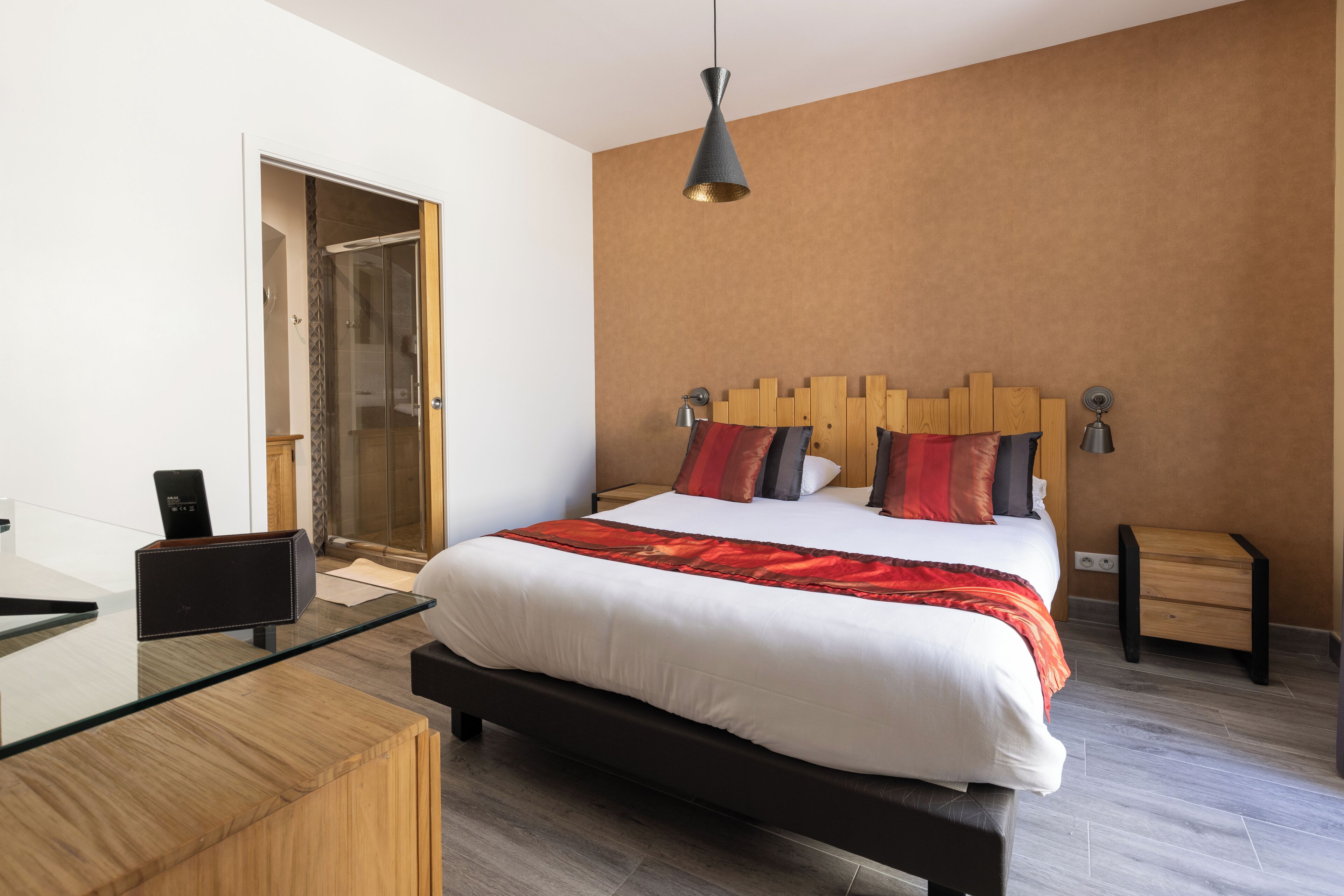 A modern hotel room with a large bed, a desk, and a shower area.