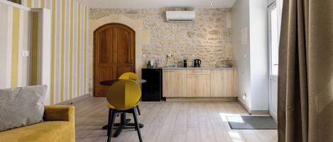 A modern kitchen with a stone wall, wooden cabinets, and a yellow chair.