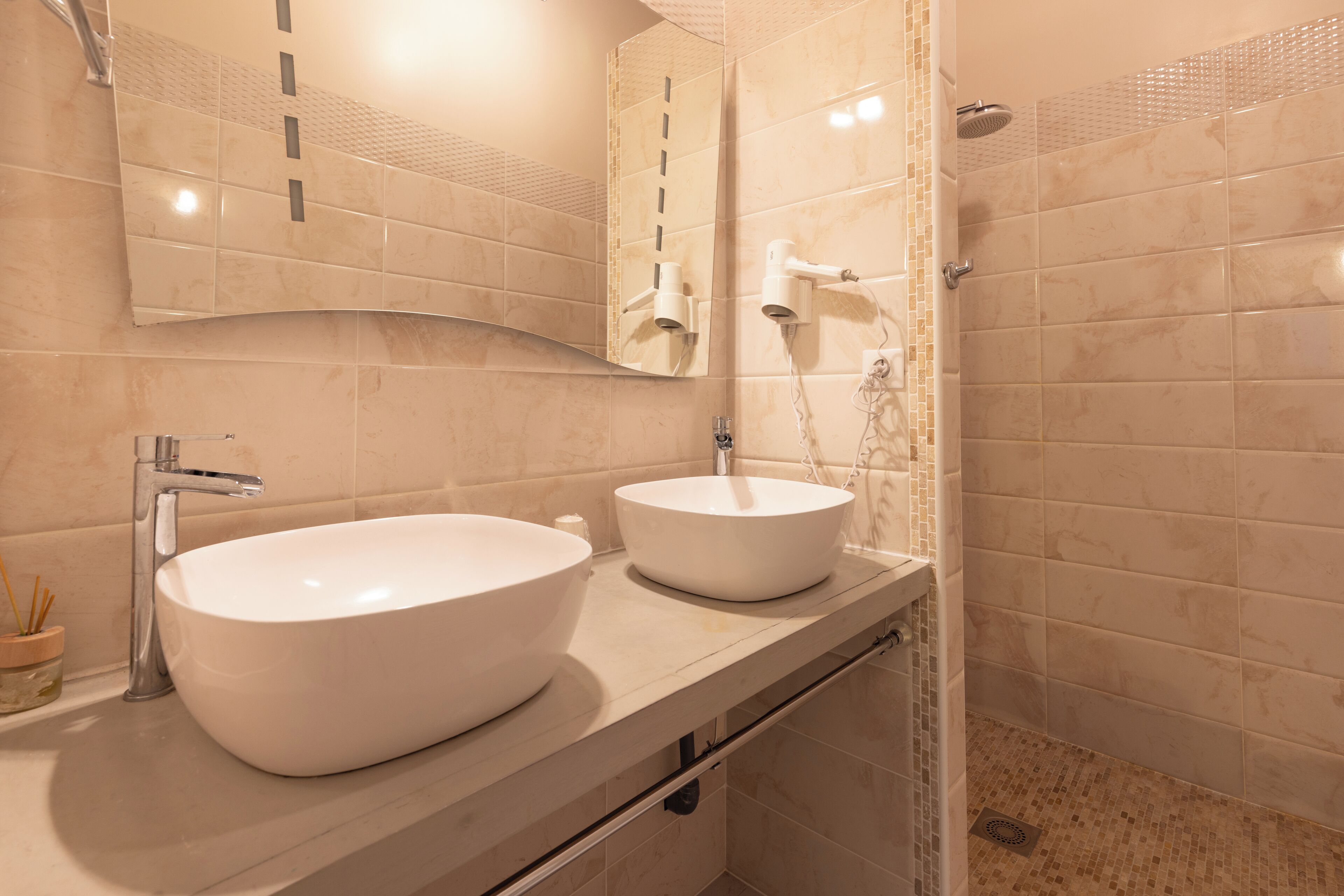 A bathroom with two sinks, a mirror, and a shower.