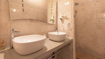 A bathroom with two sinks, a mirror, and a shower.