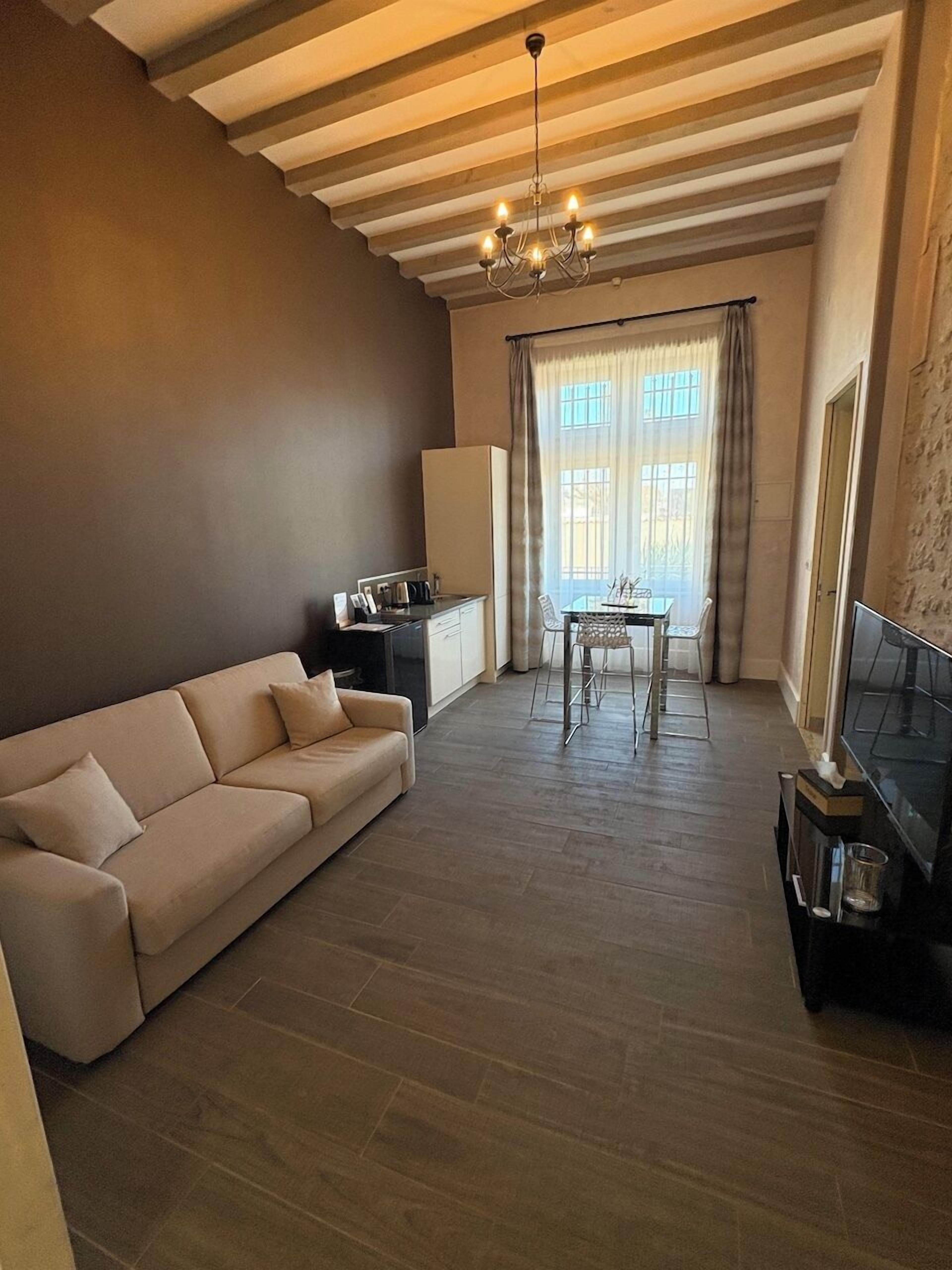 Un salon comprenant un canapé, une table à manger avec des chaises, un téléviseur et un coin cuisine.