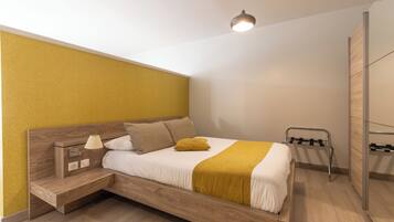 A modern bedroom with a wooden bed, a bedside table with a lamp, and a hanging light fixture.