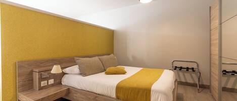 A modern bedroom with a wooden bed, a bedside table with a lamp, and a hanging light fixture.
