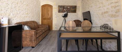 Una sala de estar con un sofá marrón, una mesa de comedor de vidrio y una puerta de madera.