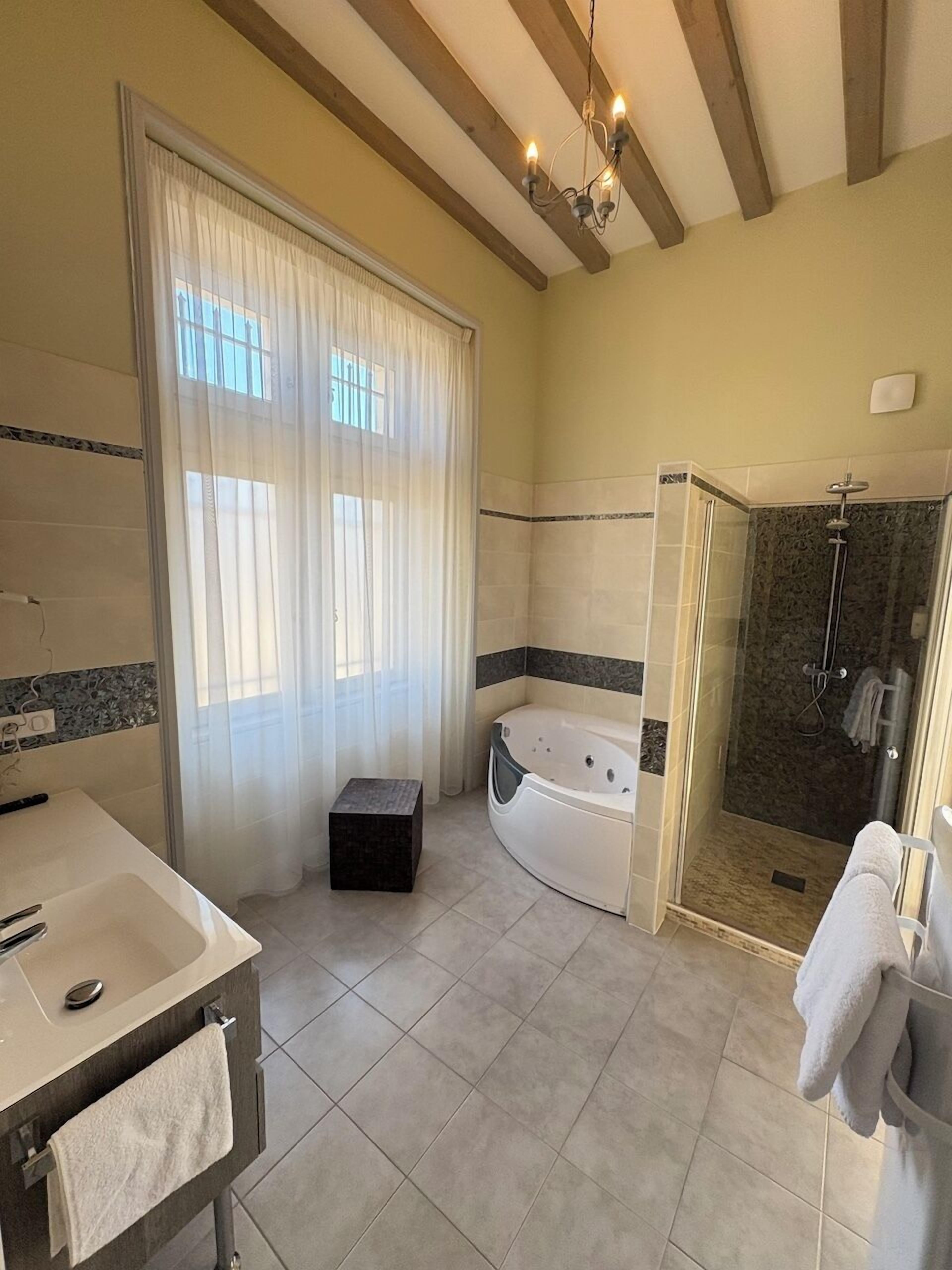 A modern bathroom with a bathtub, shower, and vanity.