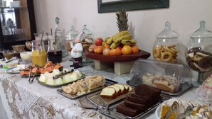 Une table de buffet proposant une variété d’aliments, notamment des fruits, des pâtisseries et des desserts.