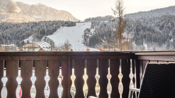Een balkon met uitzicht op een besneeuwd berglandschap.
