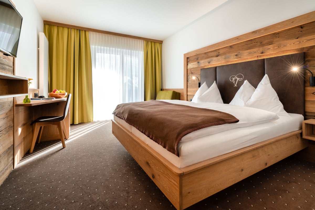 Ein modernes Hotelzimmer mit einem hölzernen Bett, einem Schreibtisch und einem Fernseher.